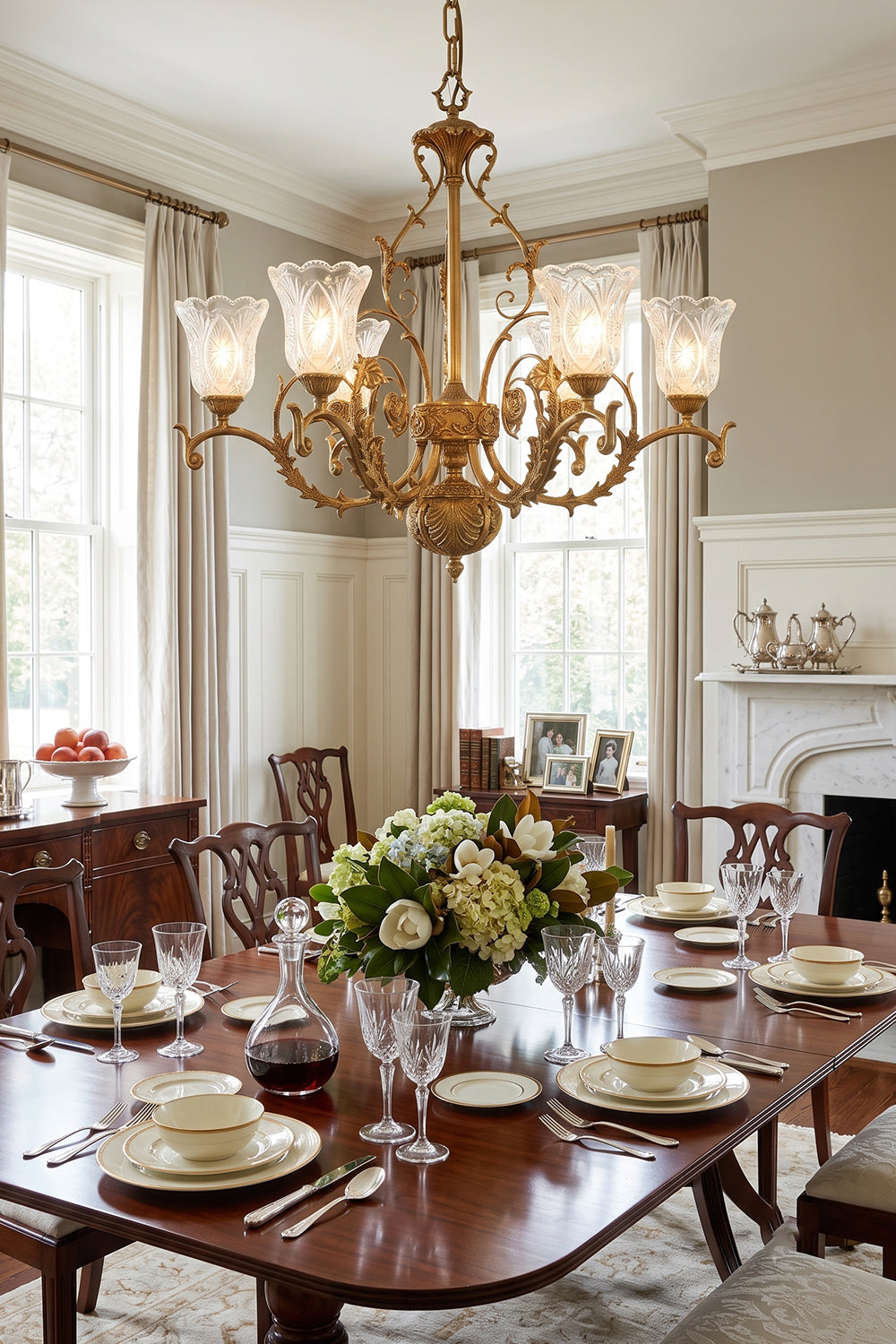 Beatrix Acanthus Leaf Chandelier | Ornate Brass and Frosted Carved Glass | Illuminating an elegant formal dining room set with a wooden table, cozy fireplace, and large windows | Samu Lamp