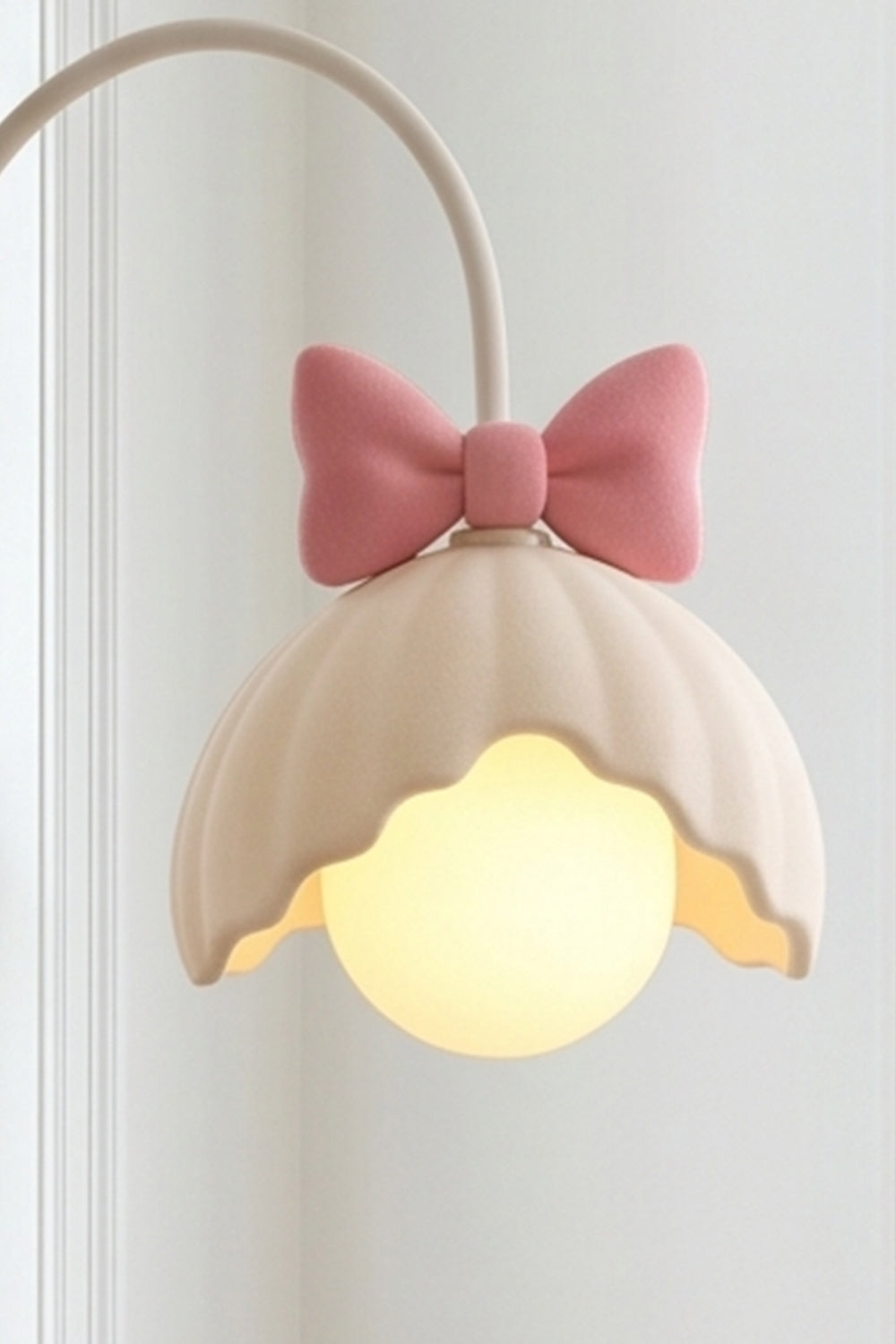 Bella Bow Arched Floor Lamp | Metal, Resin | Close-up side profile of the lit pink bow variant showcasing the glowing round glass globe bulb under the scalloped shade | Detail shot | Samu Lamp