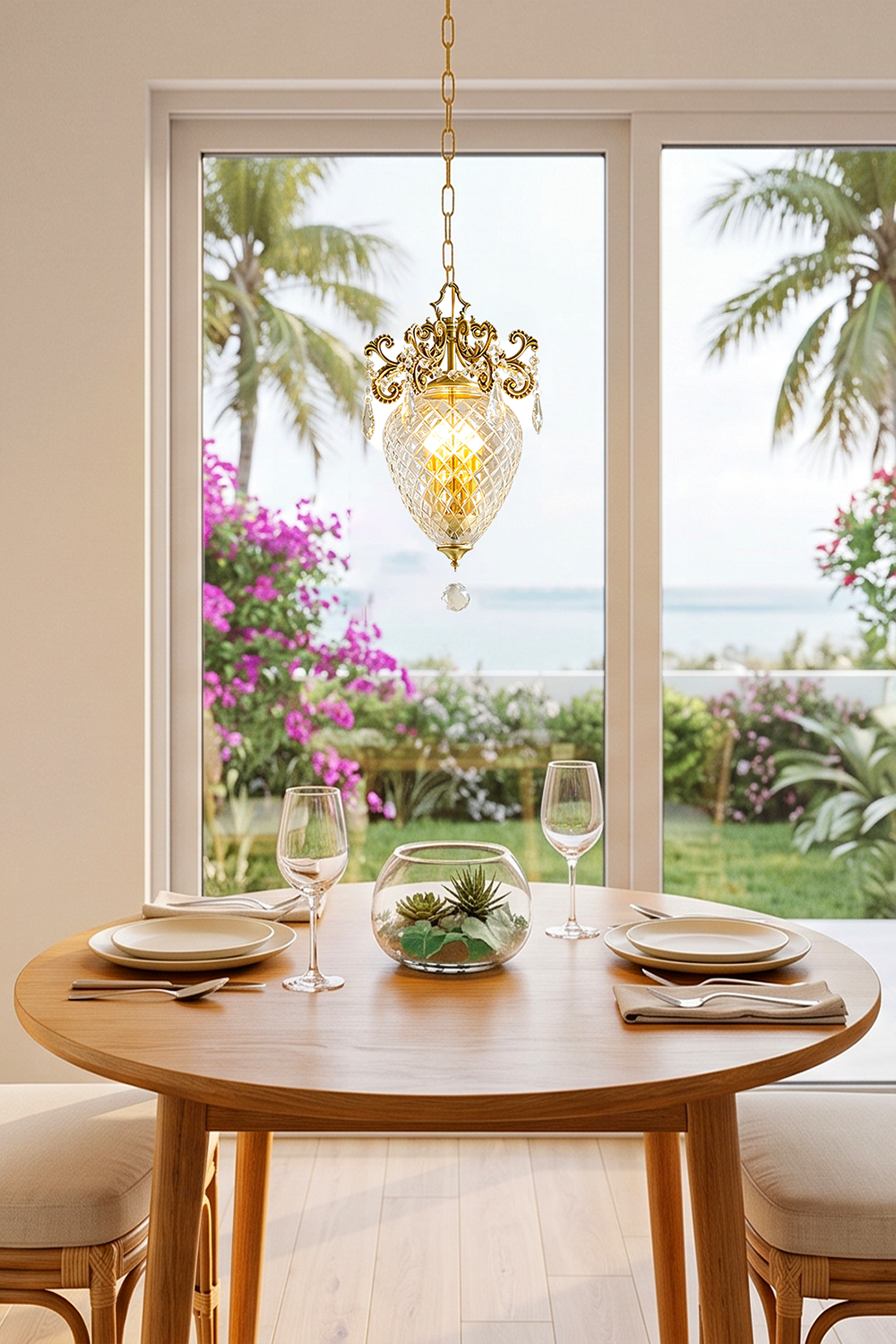 Bertrand Cut Glass Teardrop Pendant Light hanging above a dining table with views of a garden and ocean.