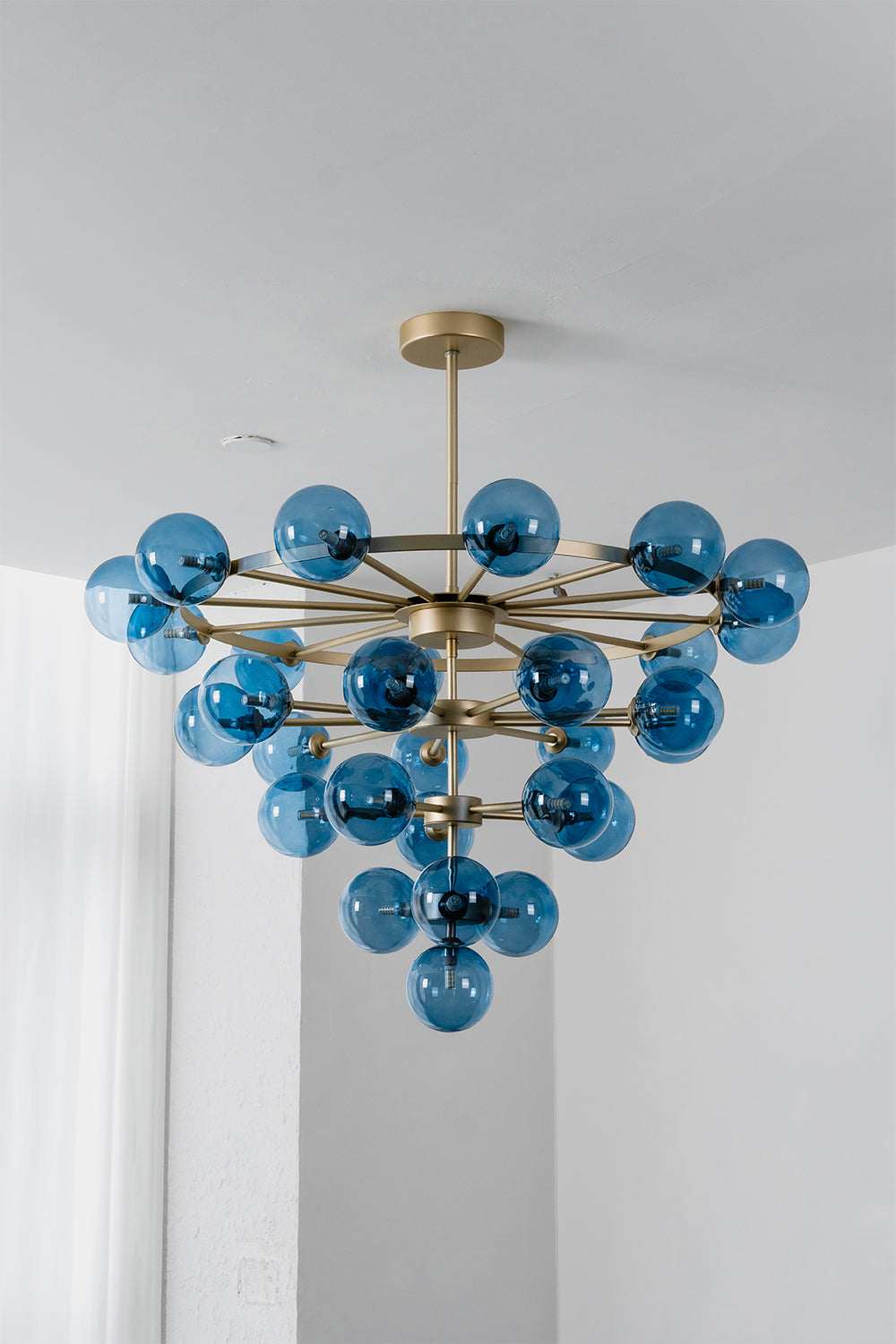 Blue Glass Bubble Globe Tiered Chandelier | Blue Glass and Brass Metal | Standard studio product shot hanging against a neutral light gray background | Samu Lamp