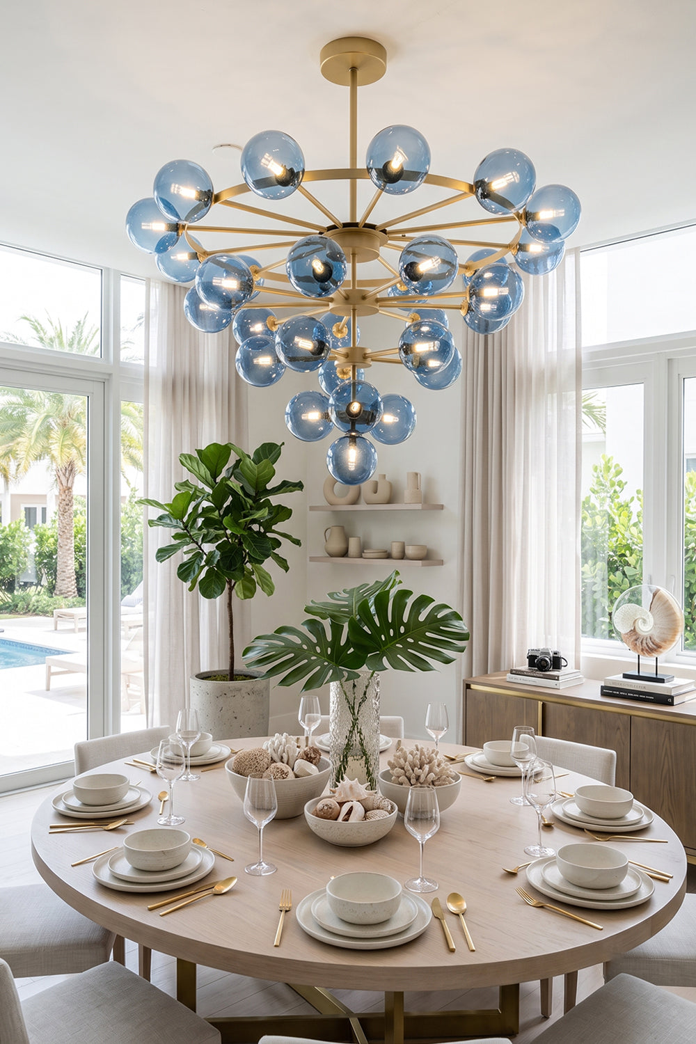 Blue Glass Bubble Globe Tiered Chandelier | Blue Glass and Brass Metal | Hanging above a beautifully set round wooden dining table in an elegant dining room | Samu Lamp