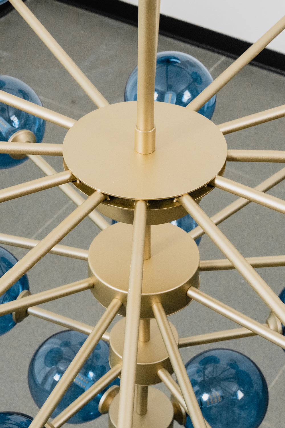 Blue Glass Bubble Globe Tiered Chandelier | Blue Glass and Brass Metal | Macro shot highlighting the central gold-finished metal hub and structural connection details | Samu Lamp