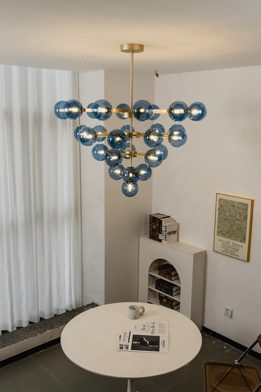 Blue Glass Bubble Globe Tiered Chandelier | Blue Glass and Brass Metal | Suspended in a minimalist white dining space above a simple round white table | Samu Lamp