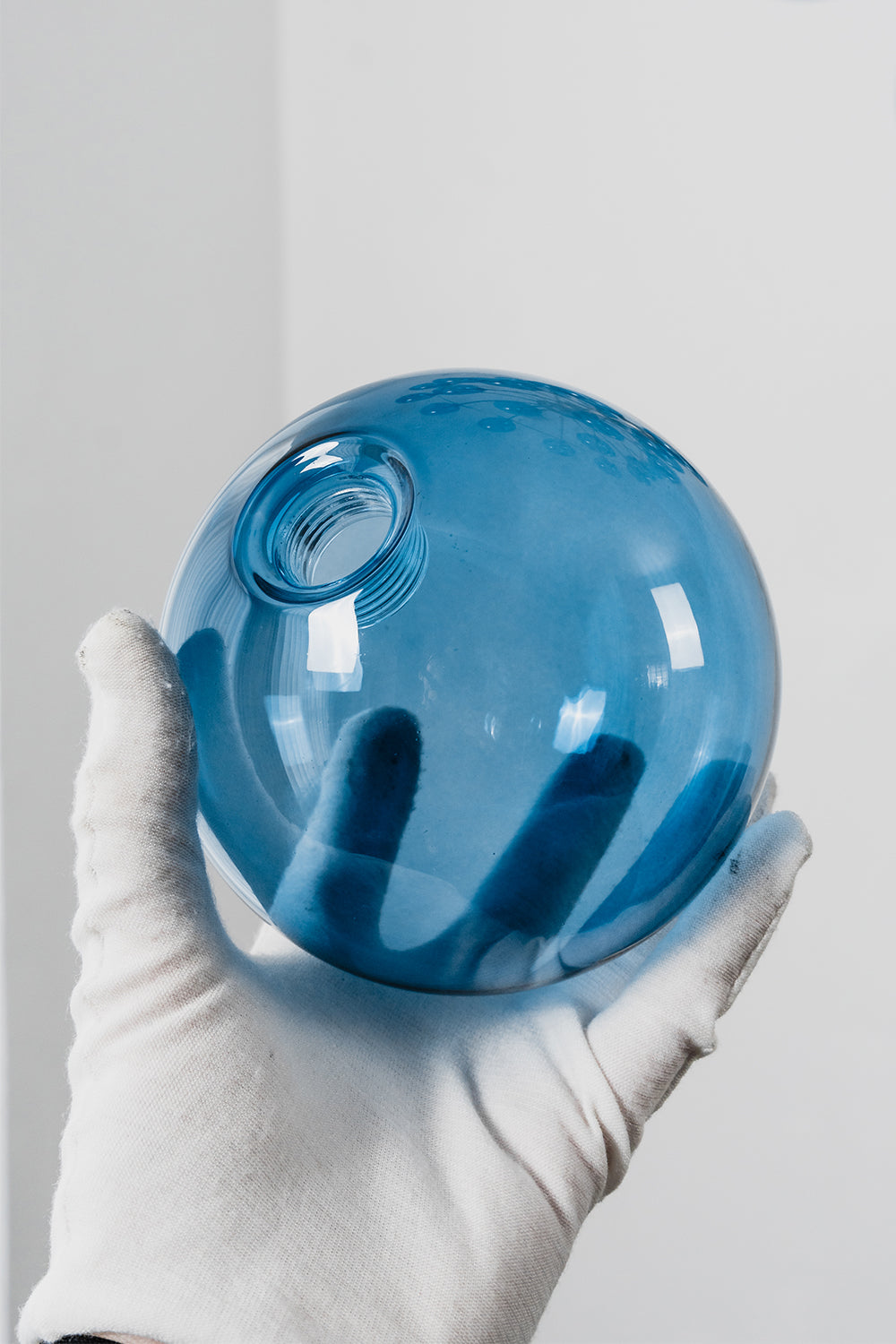 Blue Glass Bubble Globe Tiered Chandelier | Blue Glass and Brass Metal | A person wearing a white glove holding a single translucent blue glass globe sphere | Samu Lamp