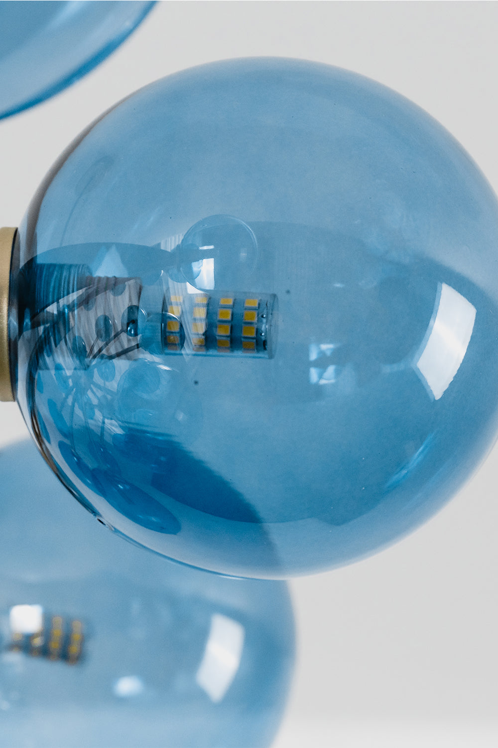 Blue Glass Bubble Globe Tiered Chandelier | Blue Glass and Brass Metal | Close-up macro detail of the vibrant blue blown glass bubbles attached to the hardware | Samu Lamp
