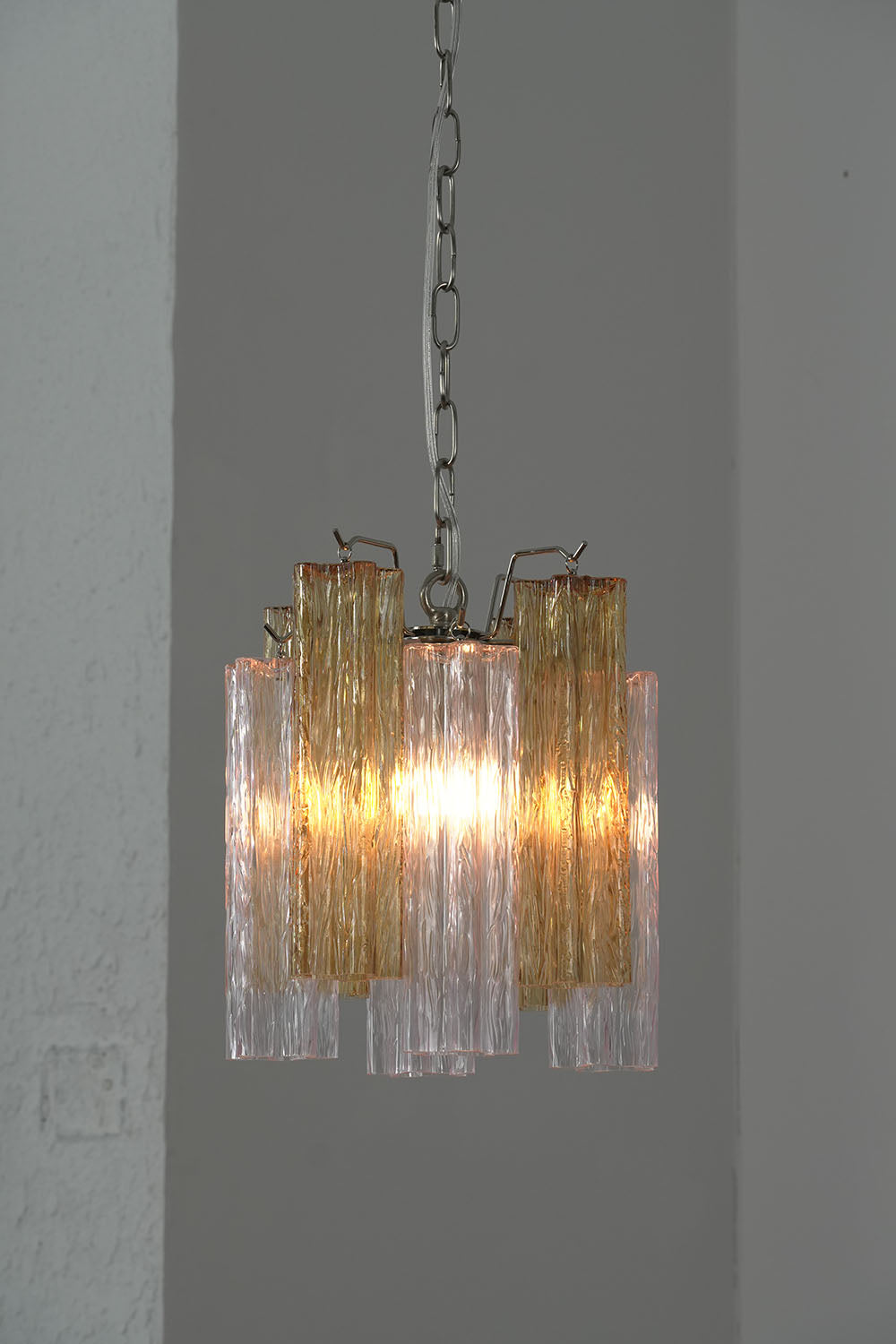 Brevalle Mini Chandelier | Textured Glass and Metal | Corner wall view illuminated with soft warm amber glow | Samu Lamp