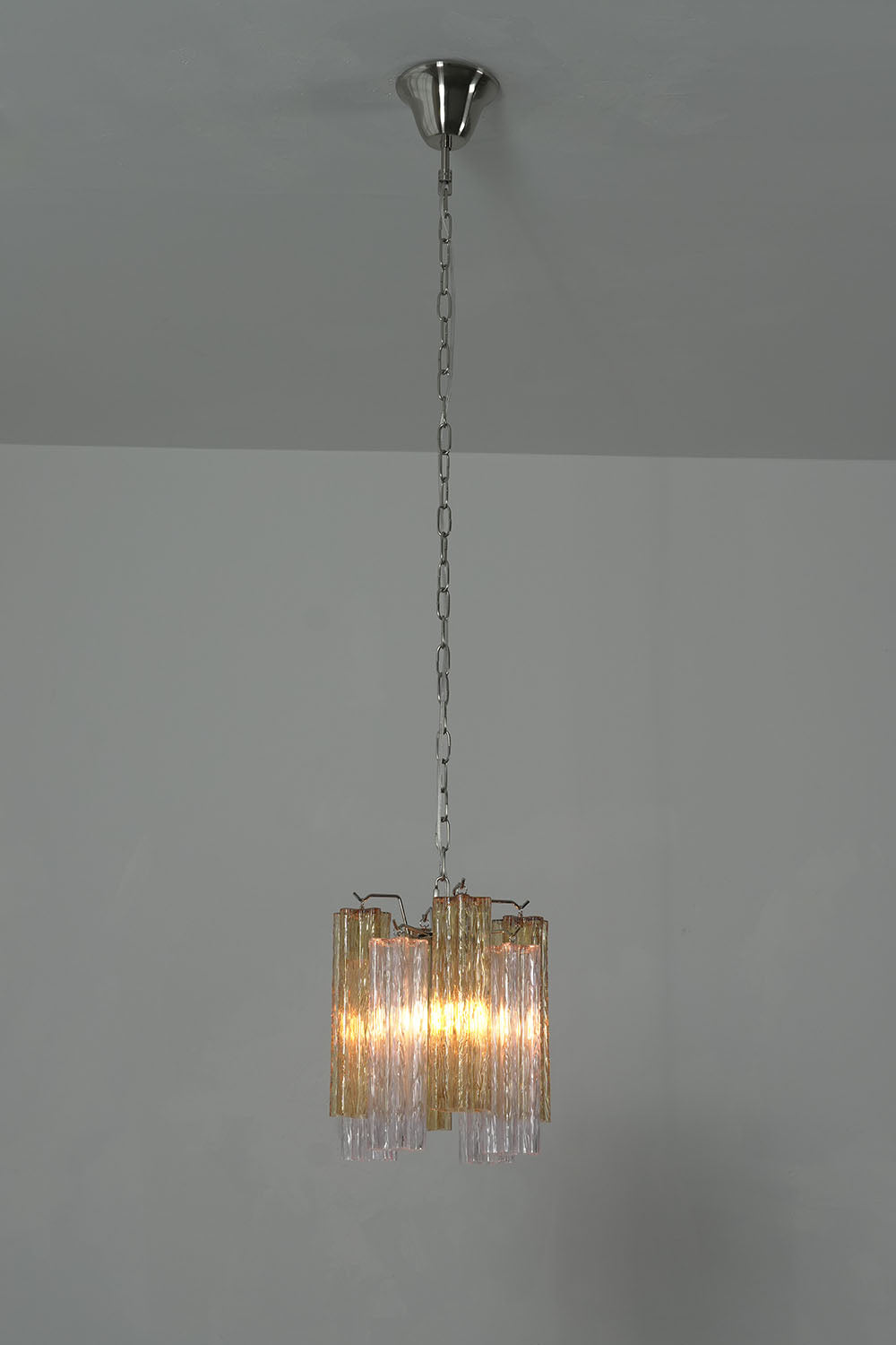 Brevalle Mini Chandelier | Textured Glass and Metal | Full hanging chain view lit against dark grey backdrop | Samu Lamp