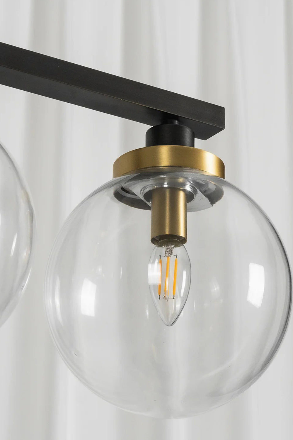 Brooks Linear Glass Globe Chandelier | Glass, Metal | Close-up unlit structural view focusing on a single transparent glass globe shade, gold collar accent, and internal filament bulb | Detail shot | Samu Lamp
