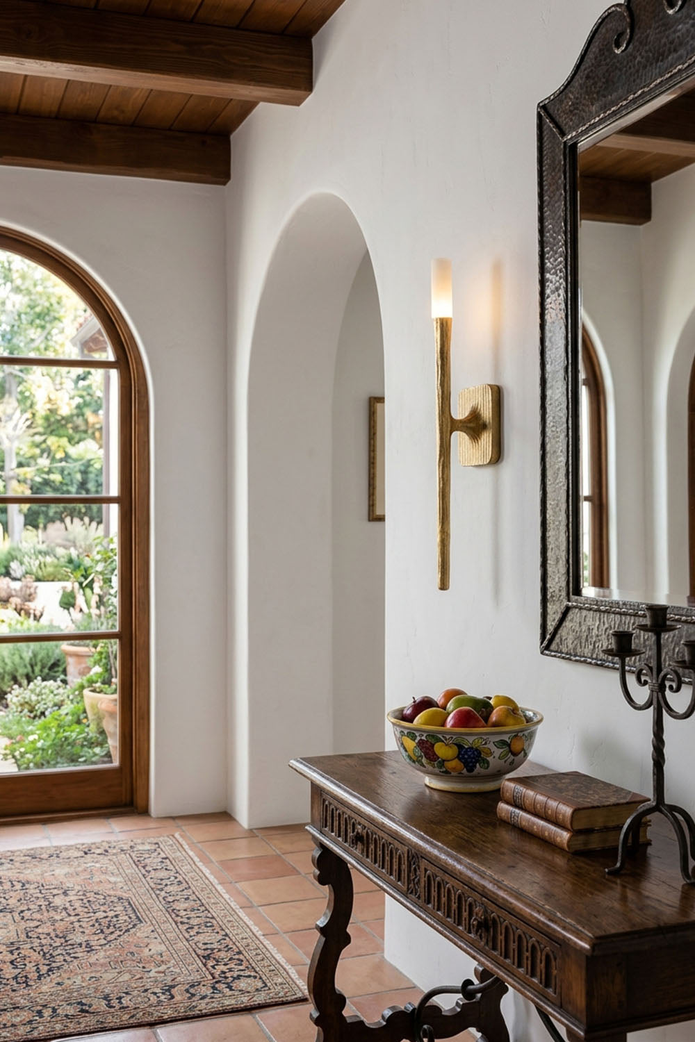 Bryony Torch Alabaster Brass Wall Lamp illuminating a hallway with a wooden console table and decor.