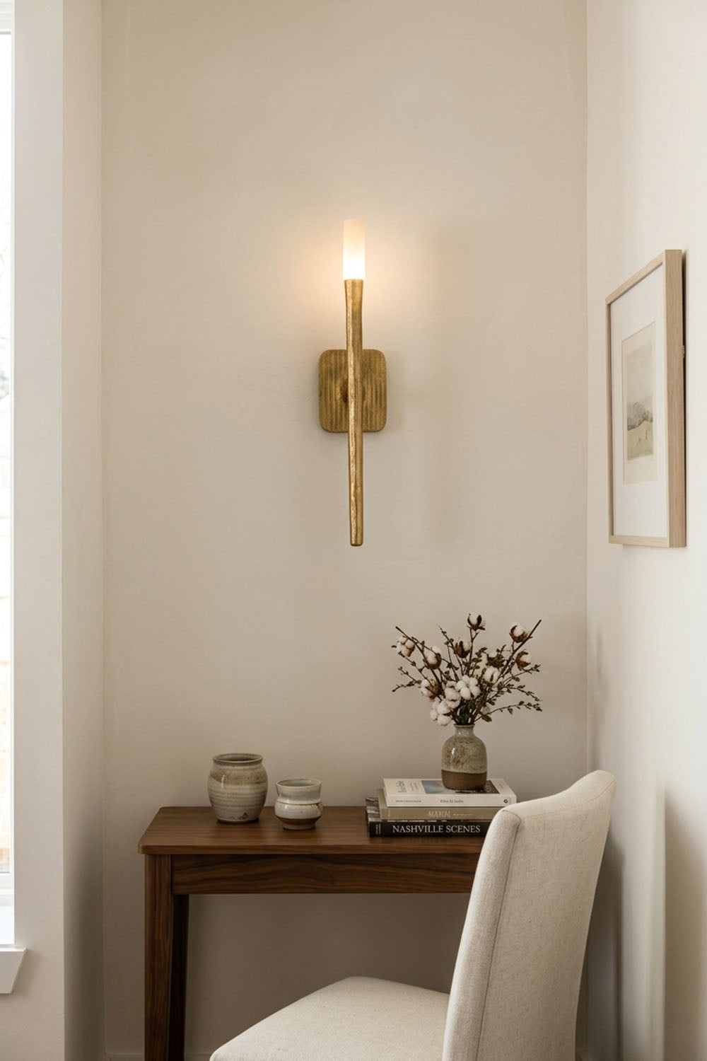 Bryony Torch Alabaster Brass Wall Lamp illuminating a cozy corner with a wooden table and chair.