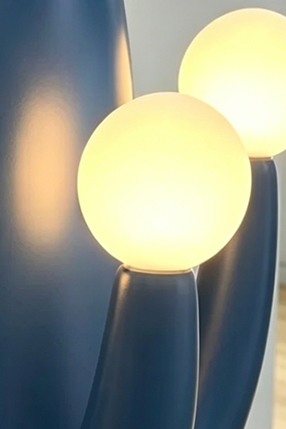 An artistic close-up perspective of a single illuminated spherical glass light bulb on the lamp, emphasizing the warm light.