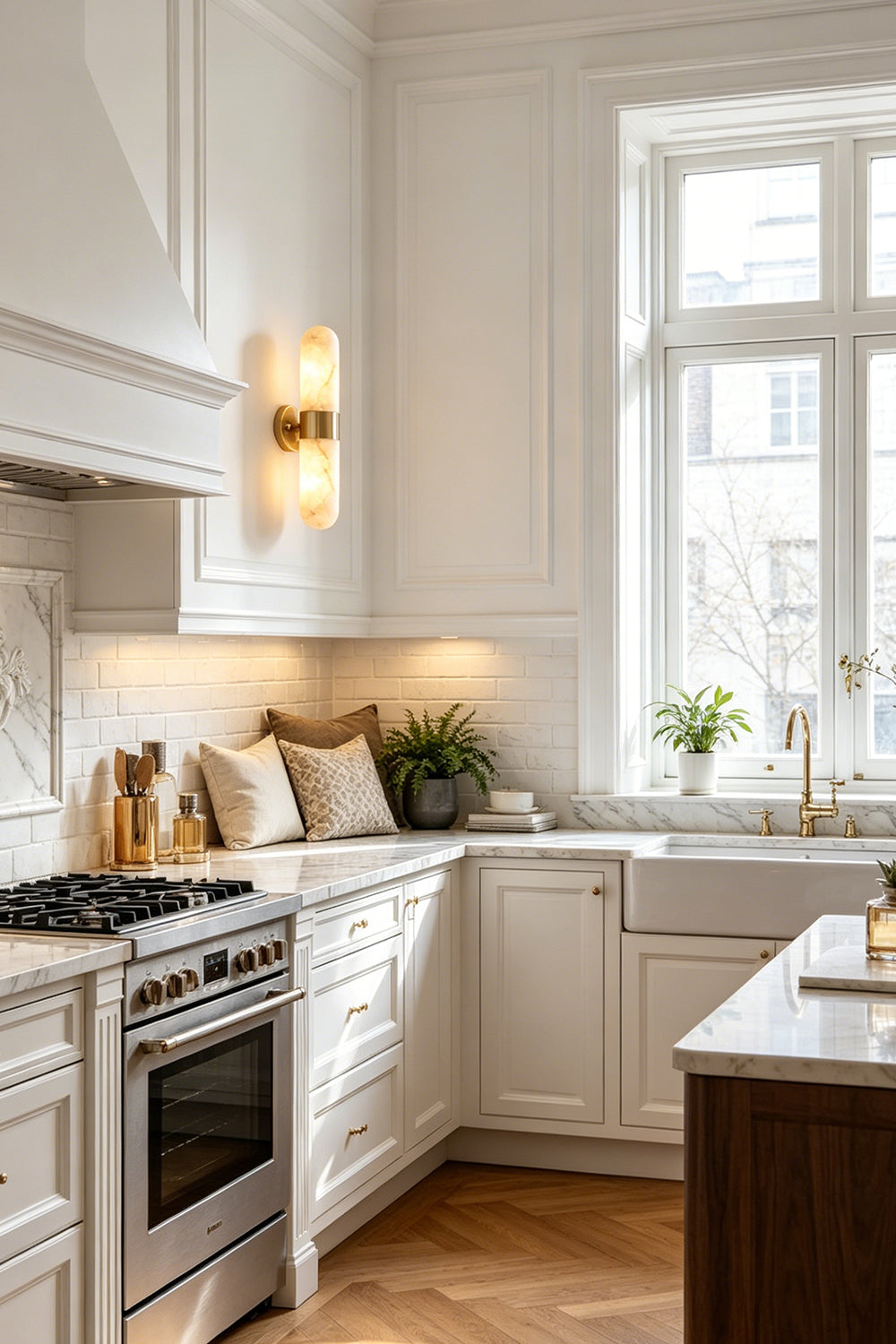 Calla Alabaster Capsule Wall Sconce | Alabaster, Brass | Illuminating a modern kitchen wall next to traditional white cabinetry and a white marble island counter | Samu Lamp