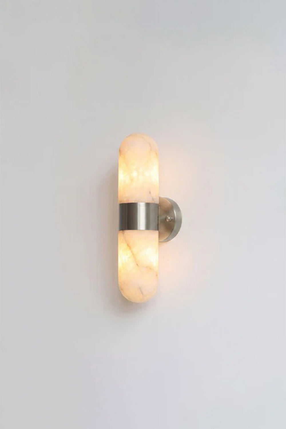 Calla Alabaster Capsule Wall Sconce | Alabaster, Metal | Fully lit studio presentation of the silver polished nickel variant on a clean light grey backdrop | Samu Lamp