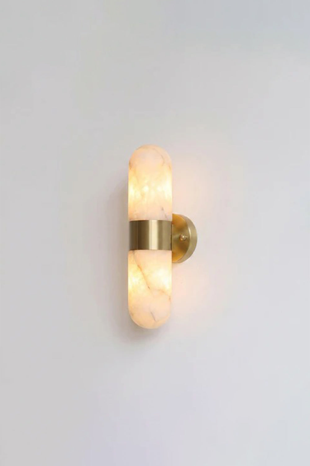 Calla Alabaster Capsule Wall Sconce | Alabaster, Brass | Fully lit studio view of the classic brushed gold brass hardware variant on a clean light grey backdrop | Samu Lamp