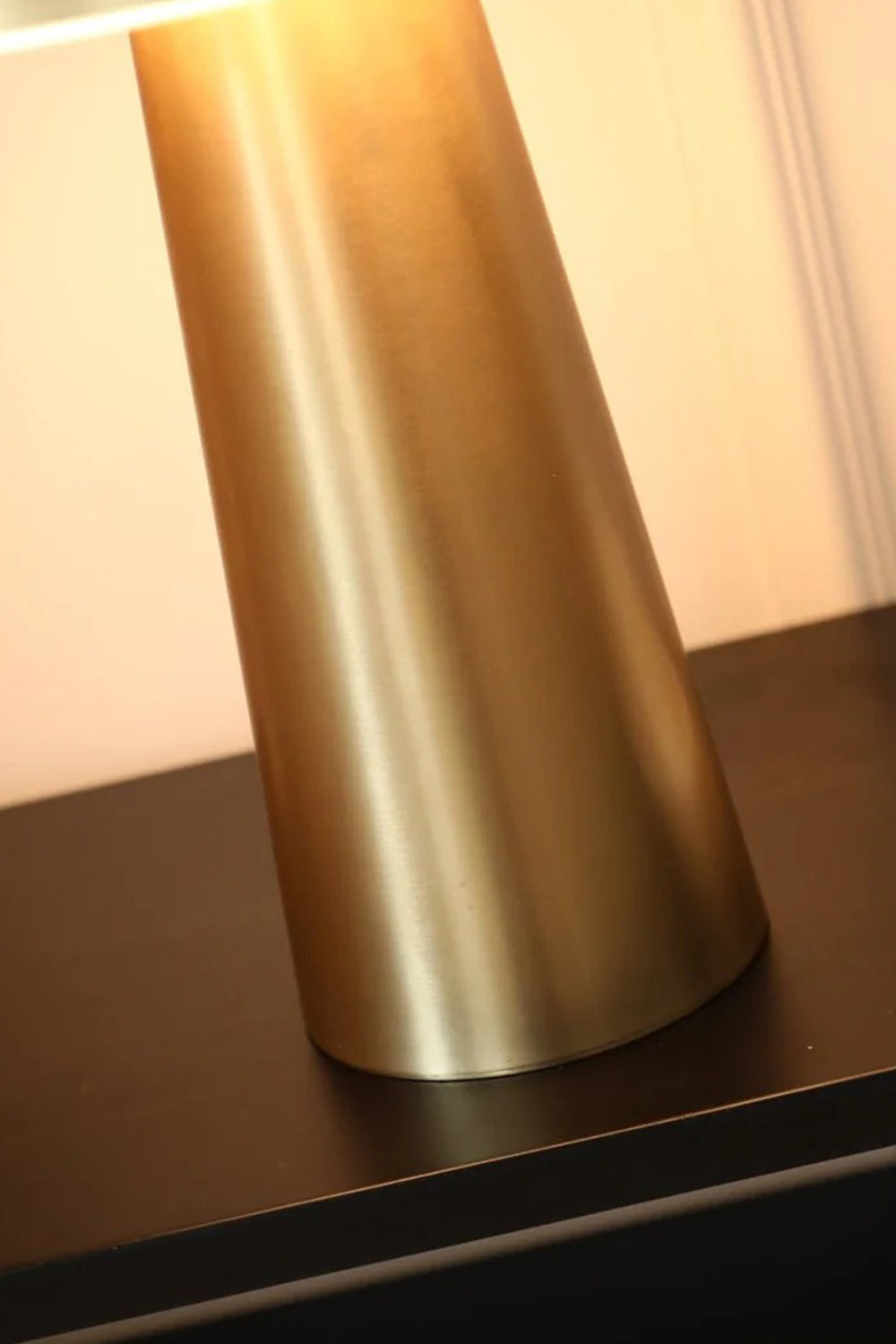 Callista Alabaster Disc Table Lamp | Tapered Base Detail | Close-up architectural focus on the heavy brushed gold brass tapered cylindrical column base resting on a dark surface | Detail shot | Samu Lamp