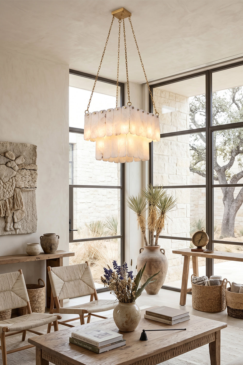 Callista Tiered Alabaster Chandelier | Alabaster, Metal | Positioned elegantly over a coffee table in a sunlit modern lounge space featuring woven pottery, plants, and lightweight lounge chairs | Samu Lamp