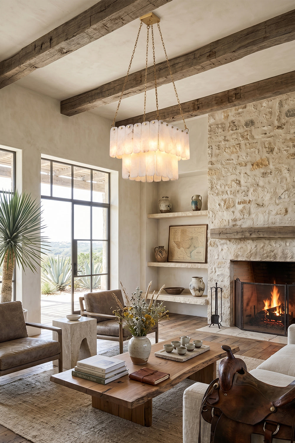 Callista Tiered Alabaster Chandelier | Alabaster, Metal | Wide-angle view of the illuminated tiered alabaster fixture in a luxurious cabin-style living room with a burning stone fireplace | Samu Lamp