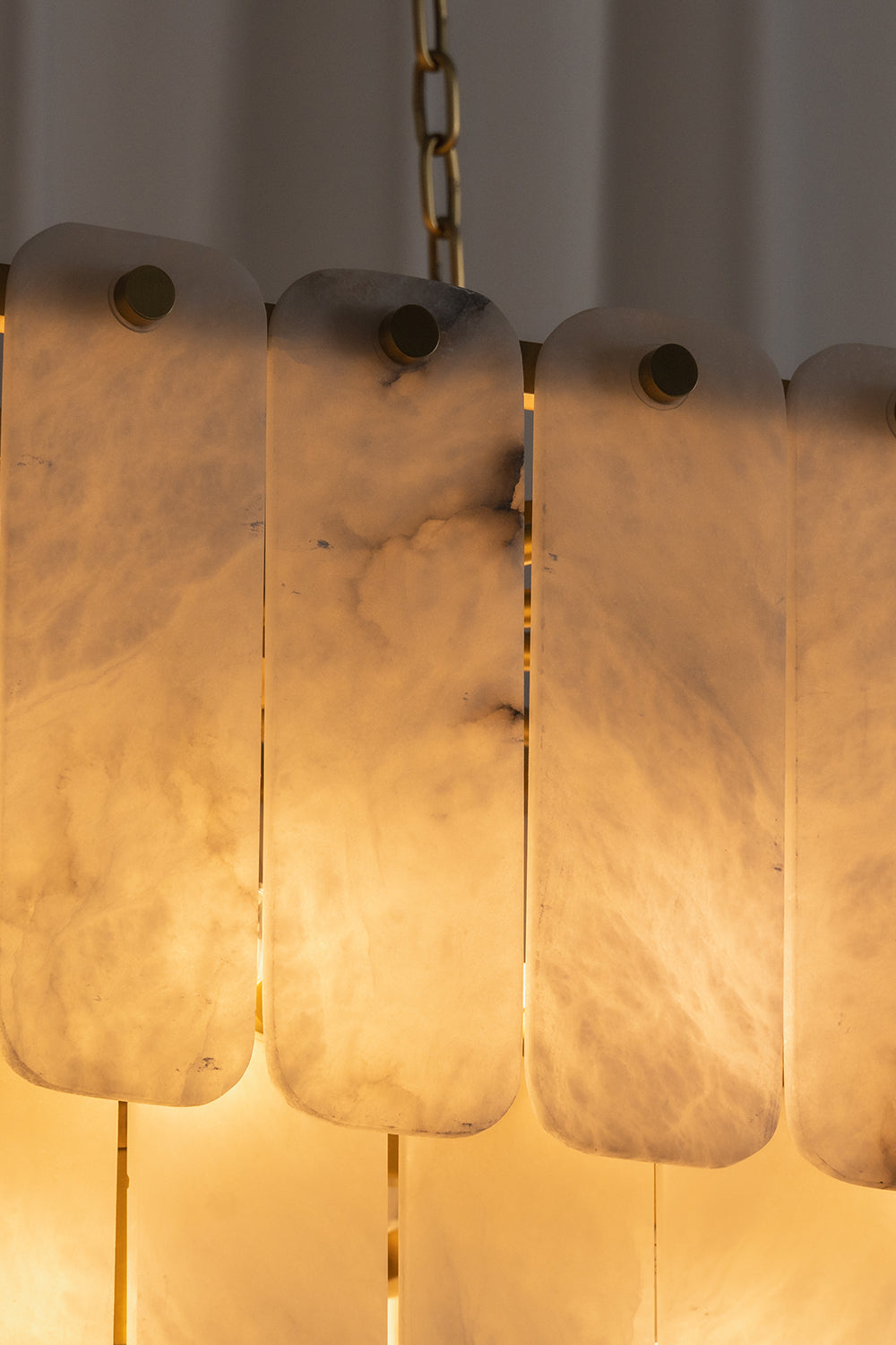 Callista Tiered Alabaster Chandelier | Alabaster, Metal | Detailed close-up view of the illuminated translucent stone tiles highlighting the rich warm light transmission and internal veining | Detail shot | Samu Lamp