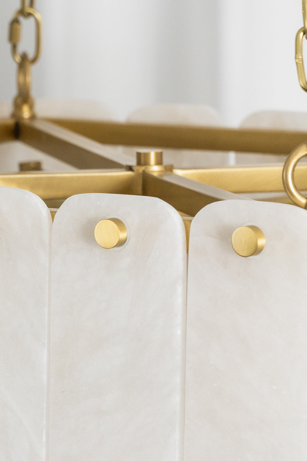 Callista Tiered Alabaster Chandelier | Alabaster, Metal | Close-up shot showing white alabaster stone slats fixed cleanly to the internal gold metal frame via round polished brass button rivets | Detail shot | Samu Lamp