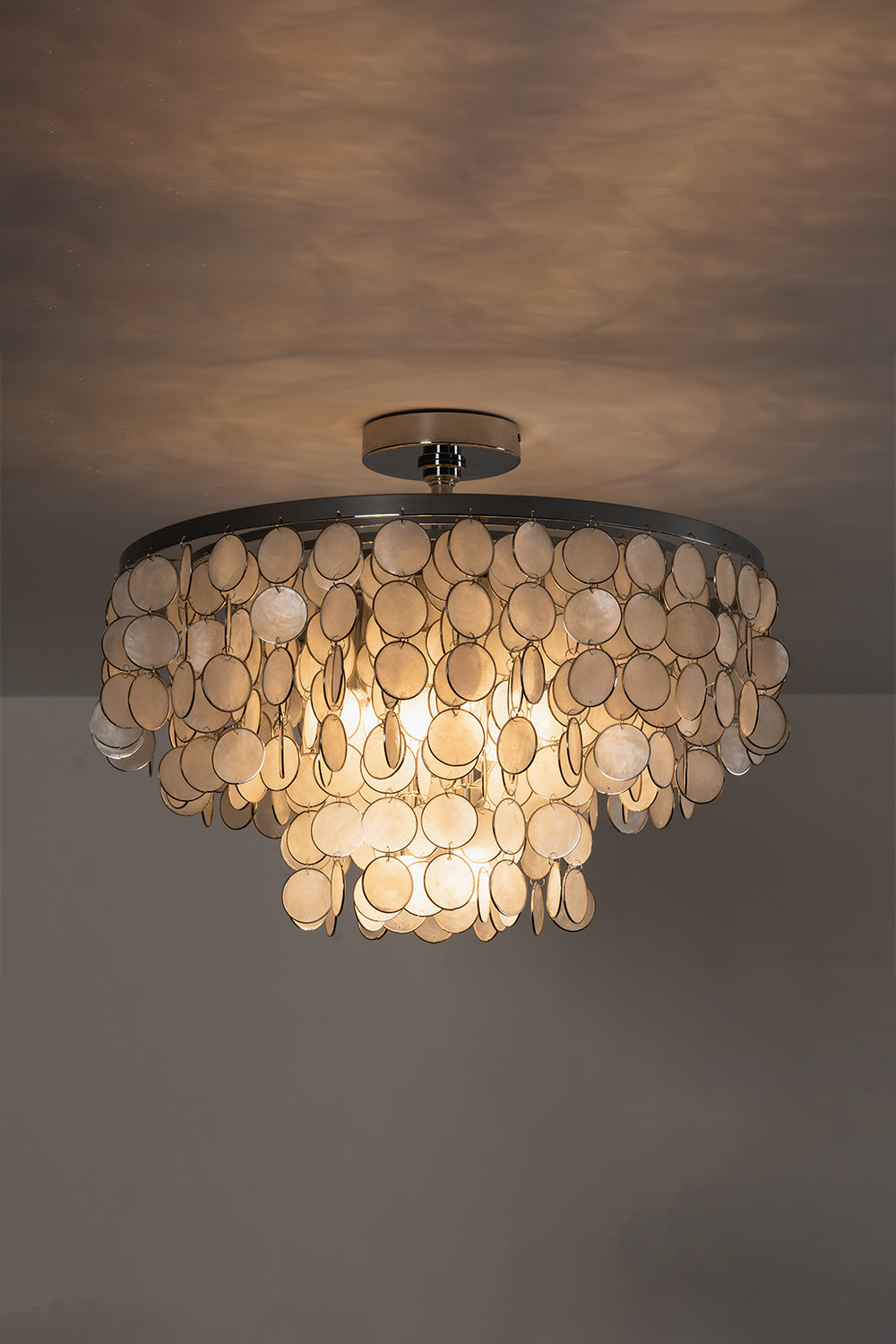 Lit Capiz shell ceiling light against ceiling | Shell | Iron | Low-light mood shot showing warm glow on textures | Samu Lamp