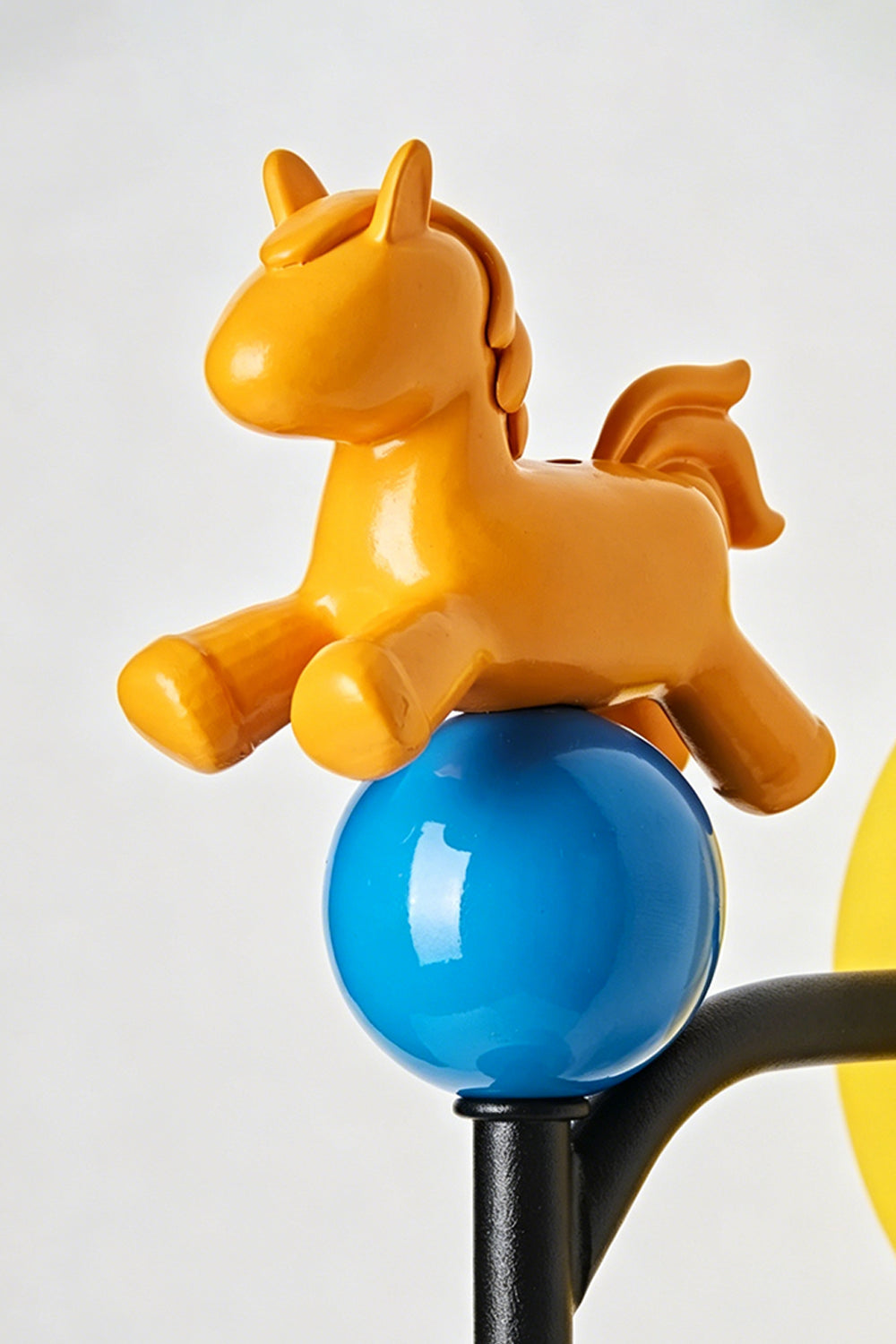 Carousel Horizon Ceramic Wall Sconce | Metal, Resin, Ceramics | Macro close-up of the playful orange resin horse perched on a glossy blue sphere | Detail shot | Samu Lamp