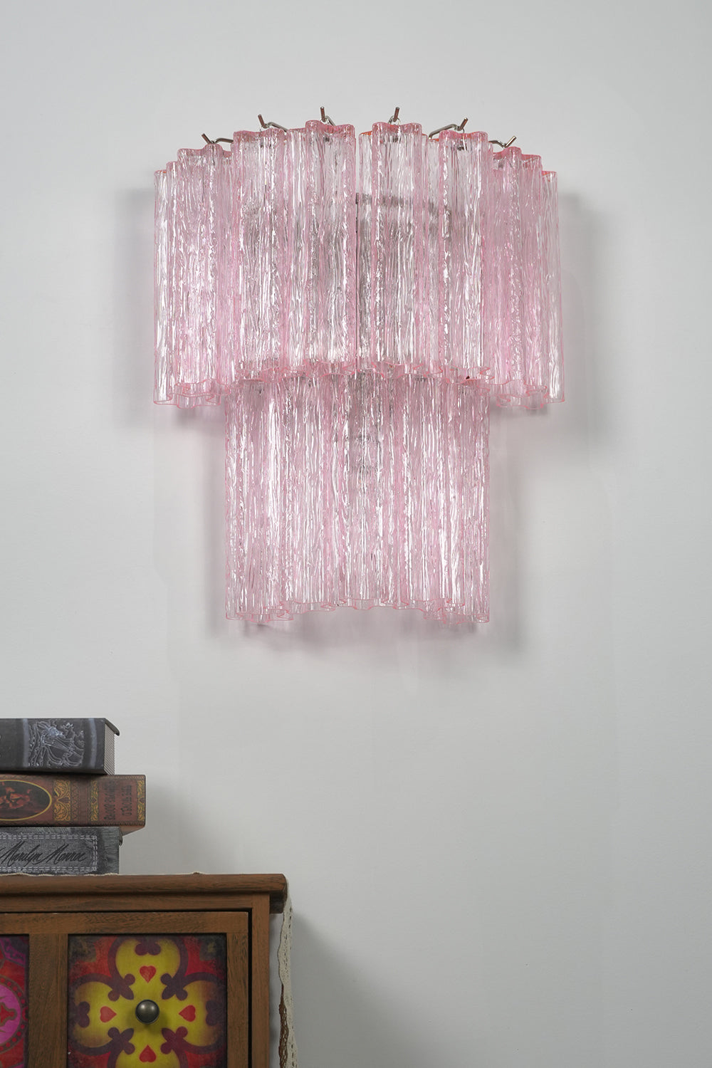Cascading Prism Pink Glass Wall Light | Glass, Metal | Front view of the unlit pink glass lamp showing its texture against a grey wall | Isolated shot | Samu Lamp Cascading Prism