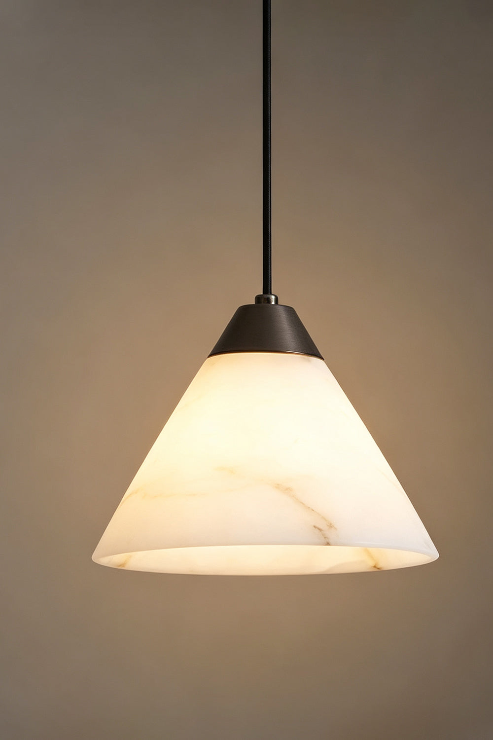 Caspian Conical Alabaster Pendant Light | Natural Alabaster and Brass | Studio view of the conical stone fixture fully illuminated against a warm grey gradient background | Samu Lamp
