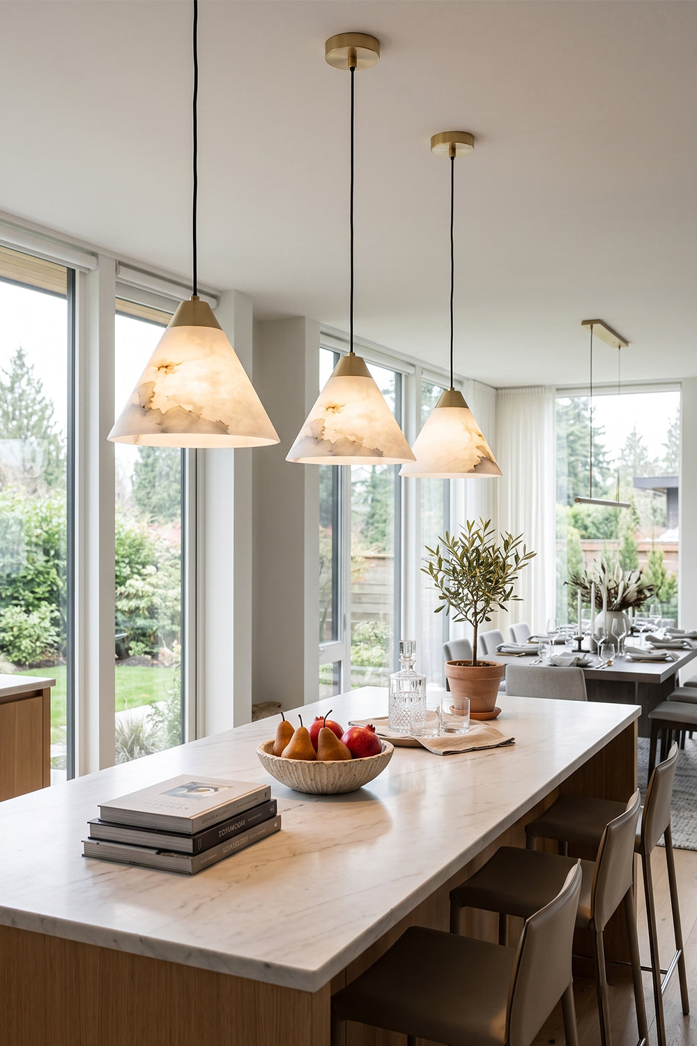 Caspian Conical Alabaster Pendant Light | Natural Alabaster and Brass | Multiple fixtures lined up nicely above a long kitchen bar dining table near large windows | Samu Lamp