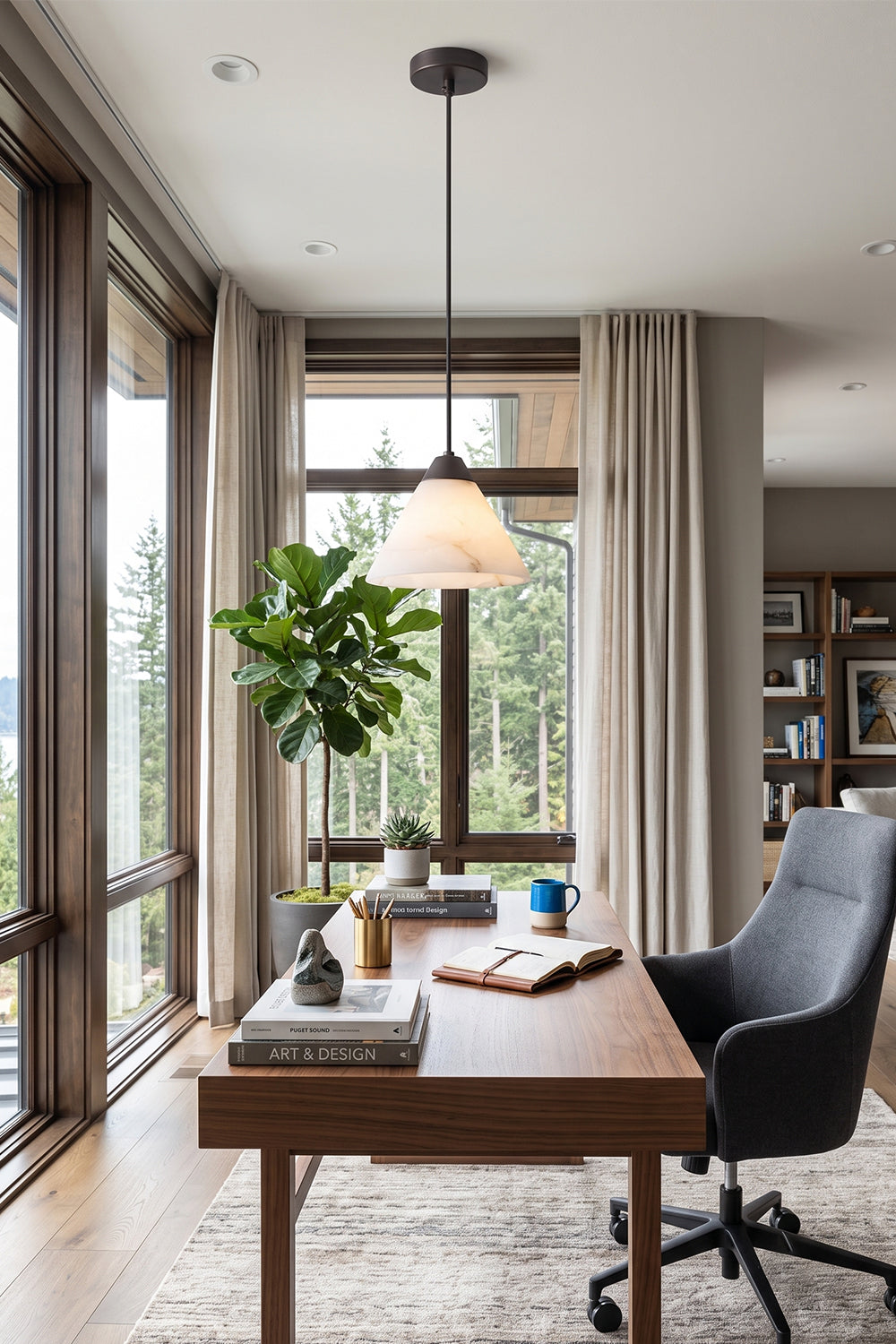 Caspian Conical Alabaster Pendant Light | Natural Alabaster and Brass | Positioned over an elegant wooden desk with a black leather chair looking out a scenic window | Samu Lamp