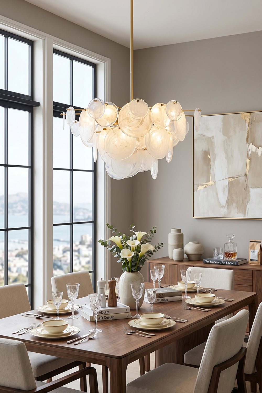 English: Celeste Glass Disc Chandelier | Glass, Metal | Illuminating a contemporary dining room setup, casting a warm ambient glow over a long wood table and minimalist chairs | Samu Lamp
