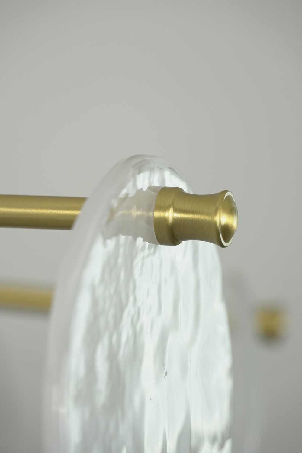 English: Celeste Glass Disc Chandelier | Glass, Metal | Detailed close-up showing a textured clear glass plate mounted securely on a gold brass rod end fixture | Detail shot | Samu Lamp