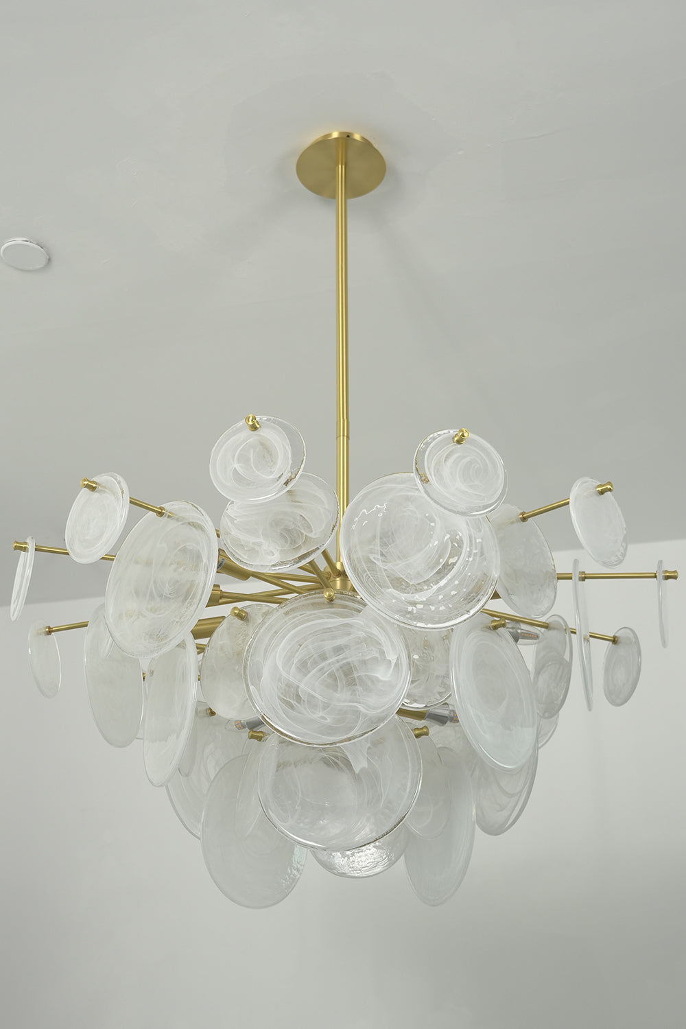 English: Celeste Glass Disc Chandelier | Glass, Metal | Unlit frontal studio view of the multi-disc organic chandelier suspended against a plain off-white background | Samu Lamp