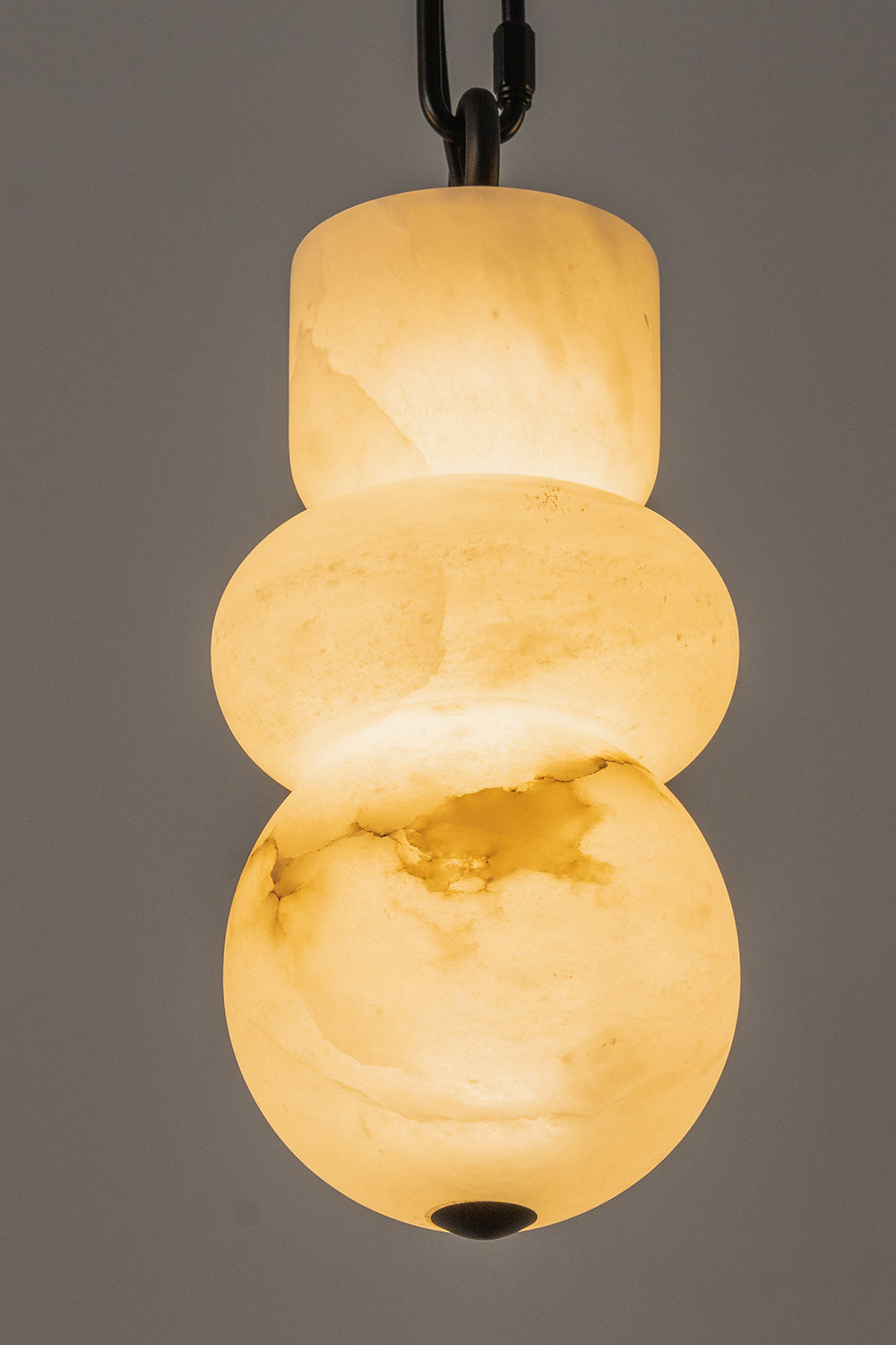 Alabaster pendant detail | Alabaster, Metal | Close-up of lit organic stone shade with black chain | Samu Lamp