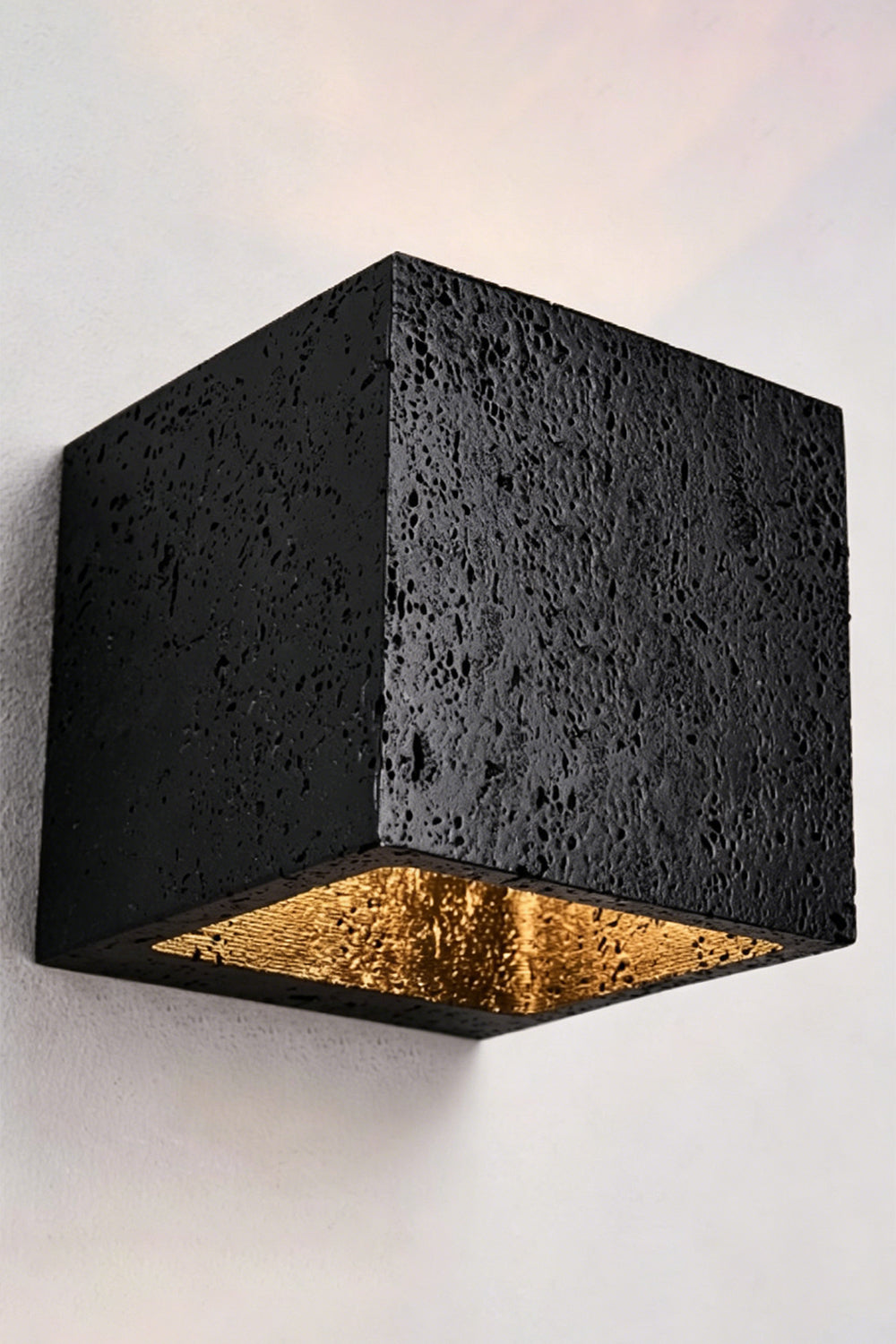 Celestial Tectonic Black Travertine Wall Lamp | Black Travertine | Lit lamp on neutral wall showing symmetric light beams | Samu Lamp