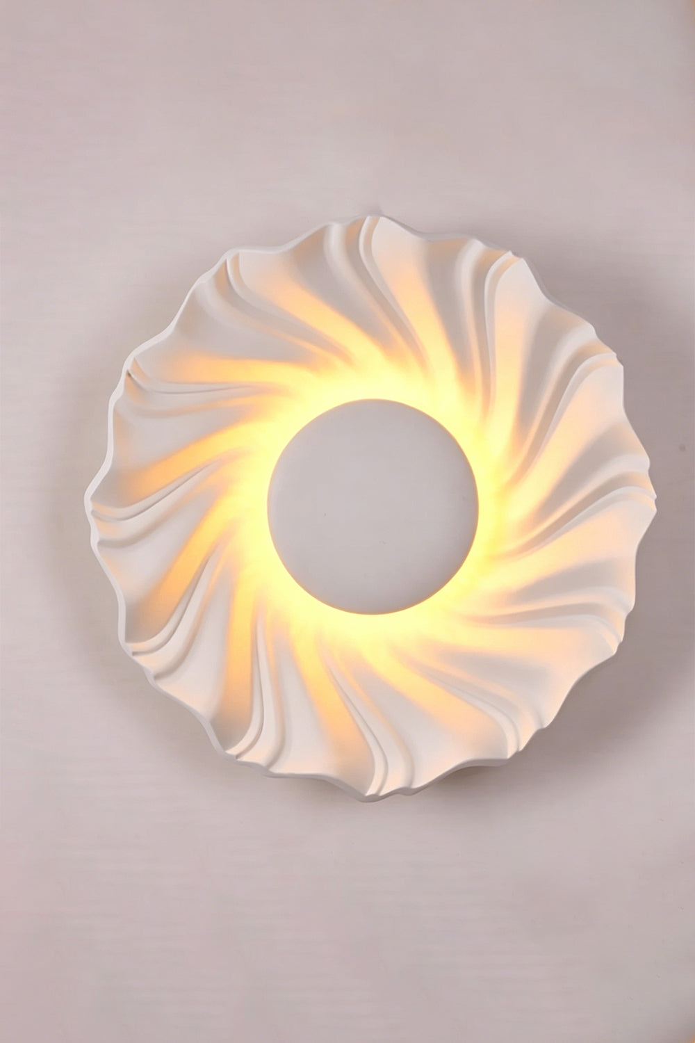 Centripetal Solstice Metal Wall Lamp | Metal, Resin | White textured lamp on a plain background, providing warm light | Isolated lit variant shot | Samu Lamp
