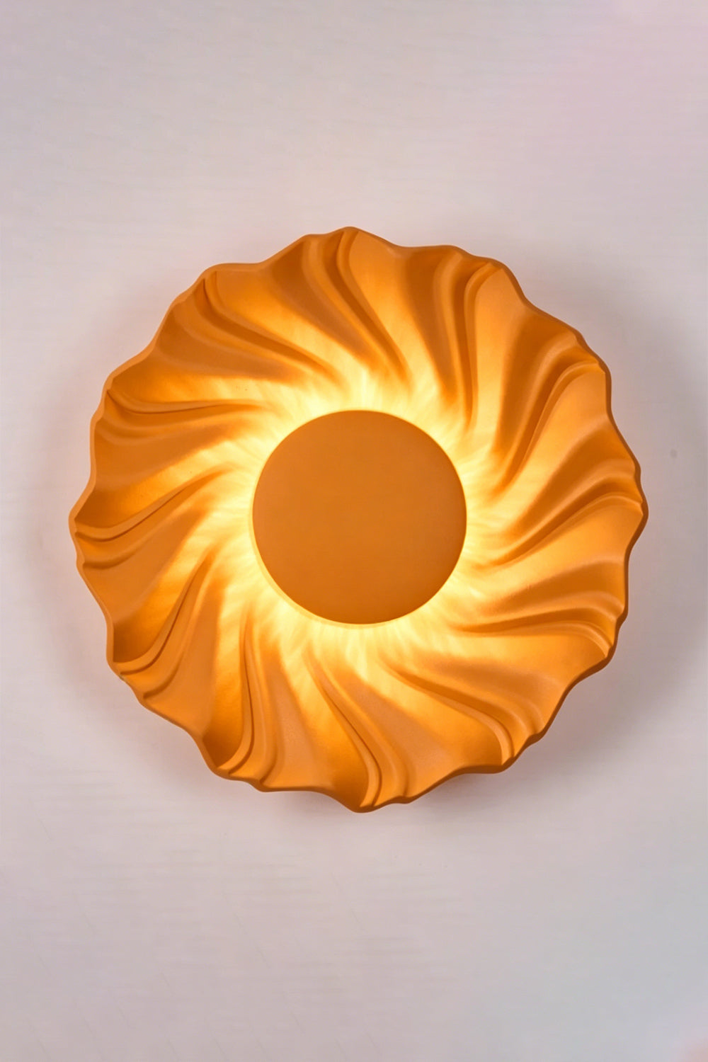 Centripetal Solstice Metal Wall Lamp | Metal, Resin | Orange textured lamp on a plain background, providing warm light | Isolated lit variant shot | Samu Lamp