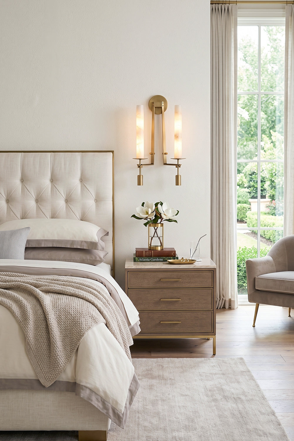 Chantal Twin Alabaster Wall Sconce | Alabaster, Brass | Mounted as a twin-light elegant bedside lamp casting a warm golden ambient glow next to a tufted cream headboard | Samu Lamp