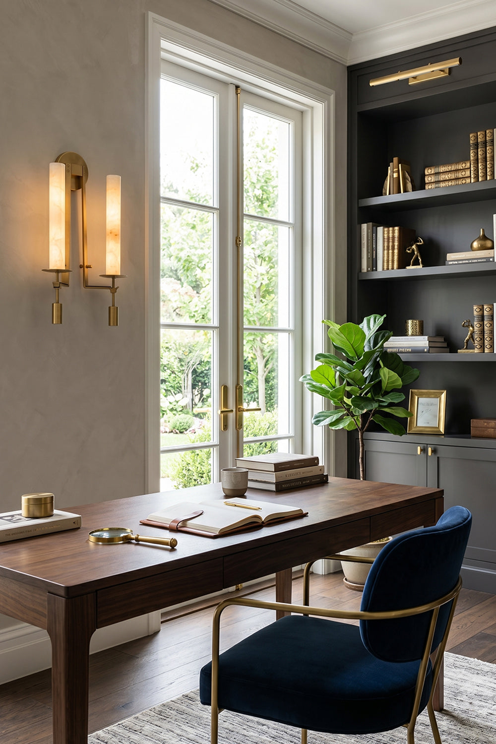 Chantal Twin Alabaster Wall Sconce | Alabaster, Brass | Providing sophisticated accent lighting in a home library office next to a dark wood executive desk and a plush navy blue chair | Samu Lamp