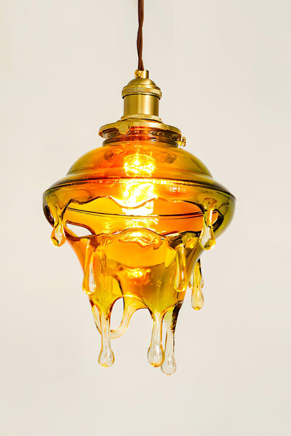 Chroma Drip Rainbow Resin Pendant Lamp | Resin, Metal | Close-up profile view of the lit amber-colored variant radiating an organic, warm golden glow from within | Detail shot | Samu Lamp