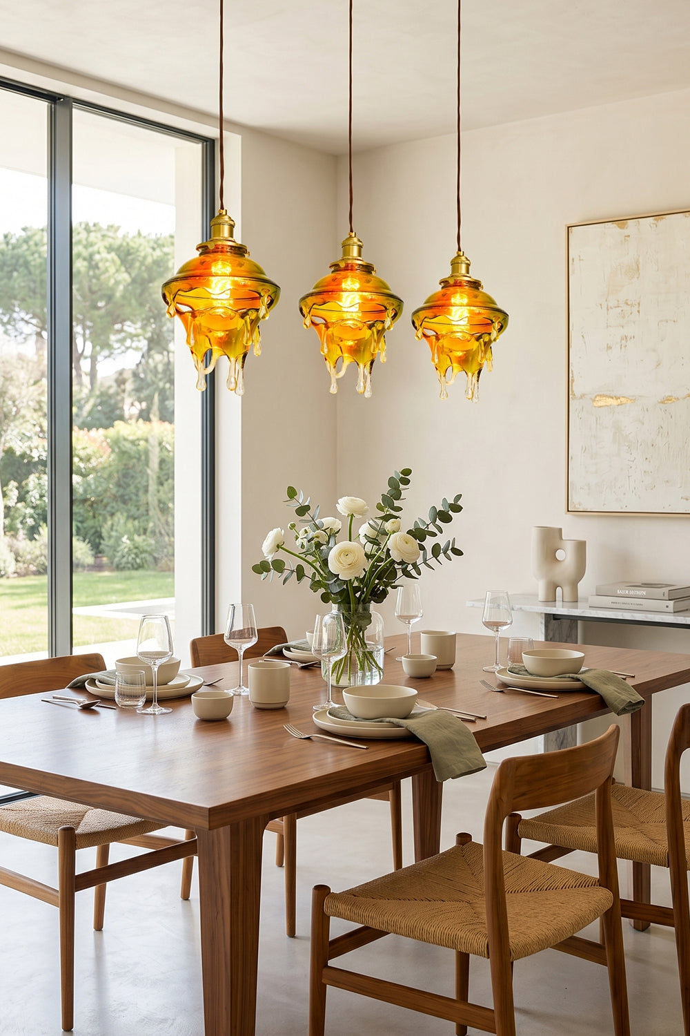 Chroma Drip Rainbow Resin Pendant Lamp | Resin, Metal | Three hanging drip pendants providing a warm amber glow over a wooden dining table and chairs near a window | Samu Lamp