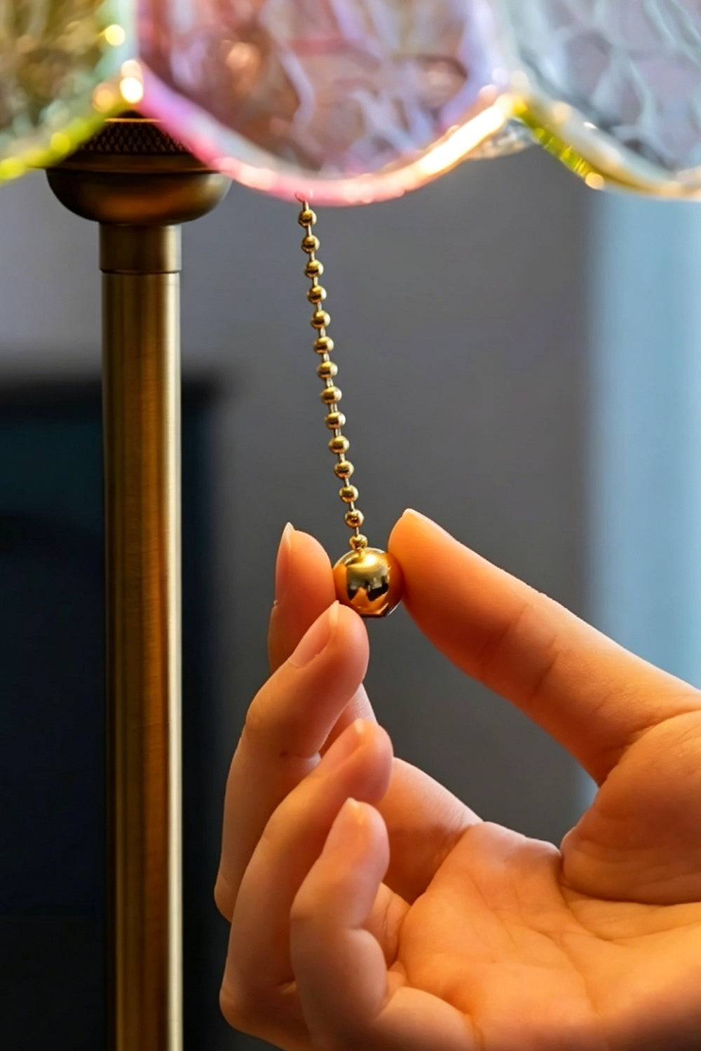 Clara Vintage Pastel Glass Table Lamp | Glass, Metal | A close-up view of a hand pulling the vintage gold ball chain switch beneath the glowing shade | Detail shot | Samu Lamp