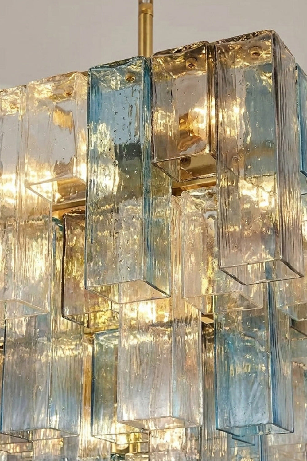Clarissa Tiered Square Glass Chandelier | Textured Glass Detail | Close-up illuminated shot focusing on the refractive light filtering through the layered blue and clear textured glass plates | Detail shot | Samu Lamp