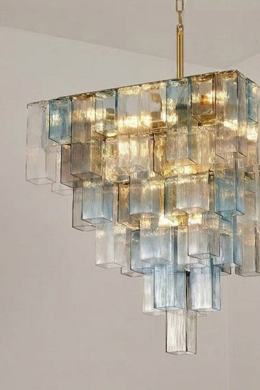 Clarissa Tiered Square Glass Chandelier | Angled Scone View | Architectural close-up view looking up at the illuminated V-shaped tiered square glass chandelier showing its geometric lines | Detail shot | Samu Lamp