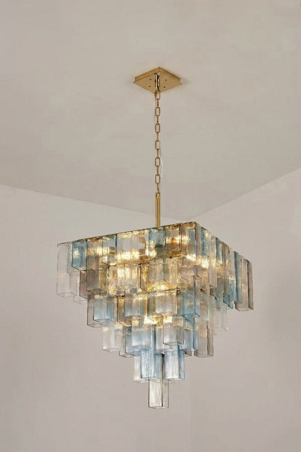 Clarissa Tiered Square Glass Chandelier | Studio Lit View | Studio presentation of the fully illuminated tiered square glass chandelier hanging against a clean off-white background wall | Samu Lamp