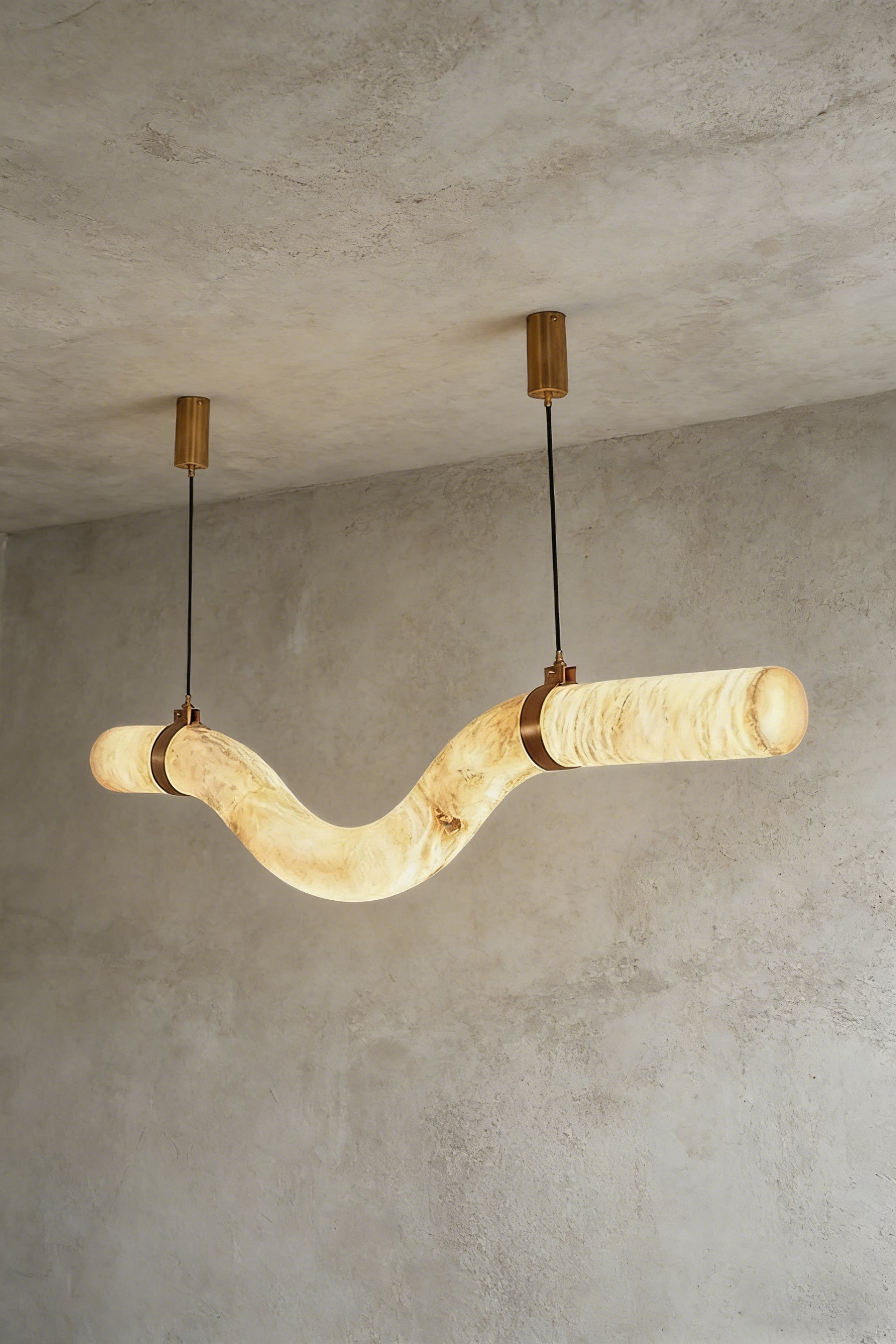 Lit undulating alabaster tube chandelier against grey ceiling | Alabaster, Brass | Side perspective showing the organic shape | Samu Lamp