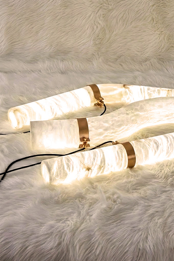 Close-up of three lit alabaster tubes on fur surface | Alabaster | Showing the natural stone grain and warm glow | Samu Lamp
