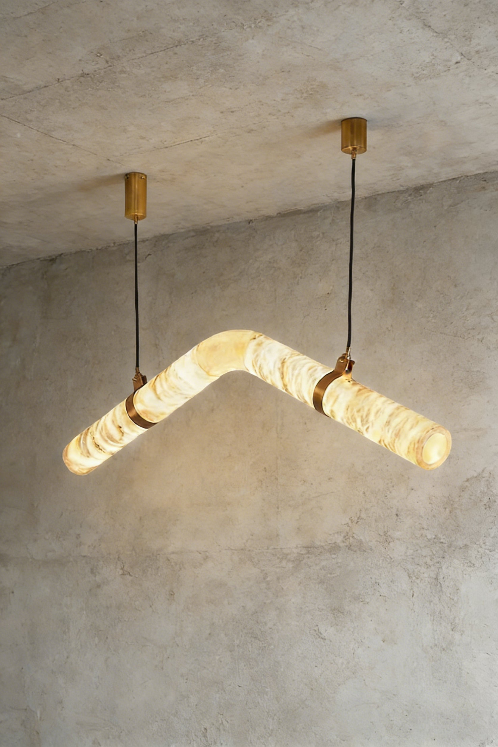 Lit undulating alabaster tube chandelier against grey ceiling | Alabaster, Brass | Side perspective showing the organic shape | Samu Lamp