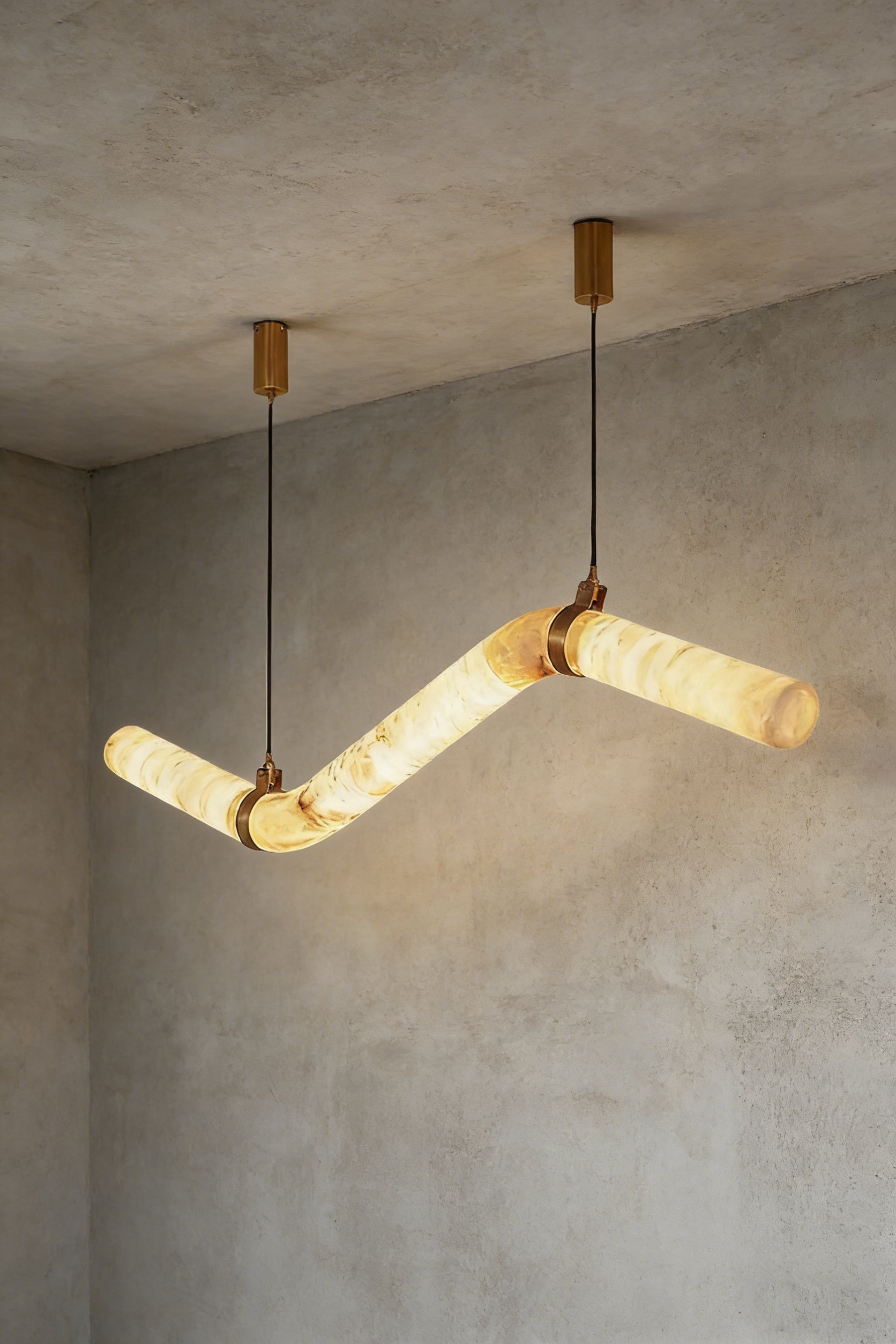 Lit undulating alabaster tube chandelier against grey ceiling | Alabaster, Brass | Side perspective showing the organic shape | Samu Lamp