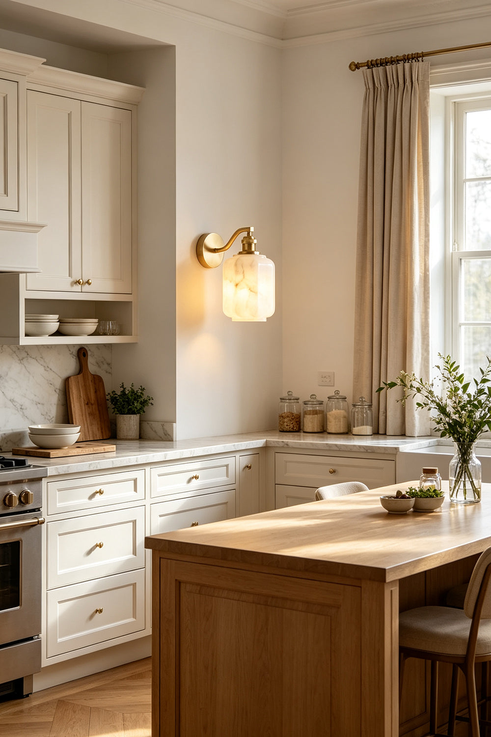 Cordelia Scalloped Alabaster Wall Sconce | Natural Alabaster and Brushed Brass | Fixed on a kitchen wall providing ambient illumination above wooden counters and an island | Samu Lamp