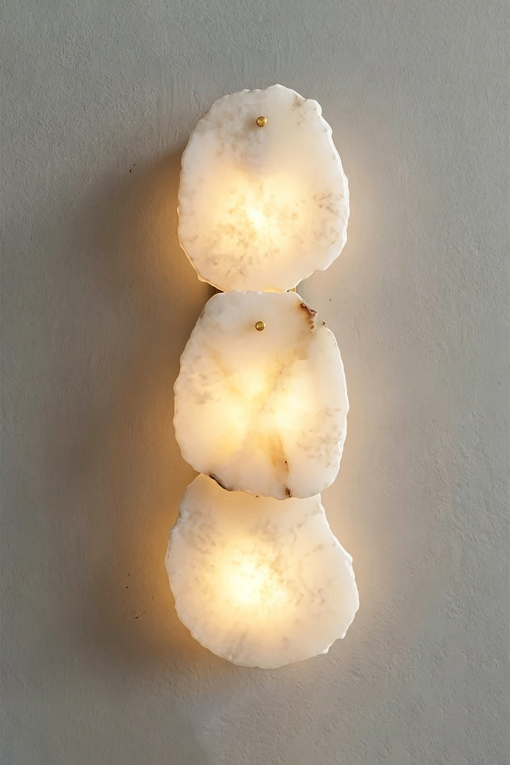 Corin Alabaster Wall Sconce featuring three oval alabaster panels emitting warm light.